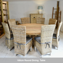Load image into Gallery viewer, 180cm round reclaimed teak  dining table with 8 kubu wicker chairs in a room setting.