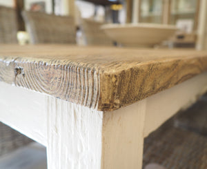 Closeup detail of rustic reclaimed pine cottage style dining table wood grain with whitewashed legs