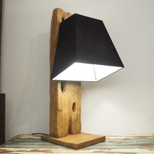 Load image into Gallery viewer, Reclaimed wood table lamp with characterful base showing original features of the timber. Shown with a black lampshade on a wooden table and a plain background.
