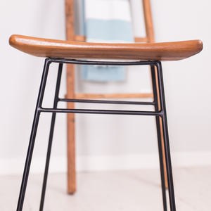 Close-up view of the solid teak wood seat of a bar stool.