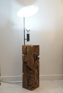 uplighter style floor lamp featuring a chunky wooden base crafted from naturally shaped pieces of teak wood cut as a square column.
