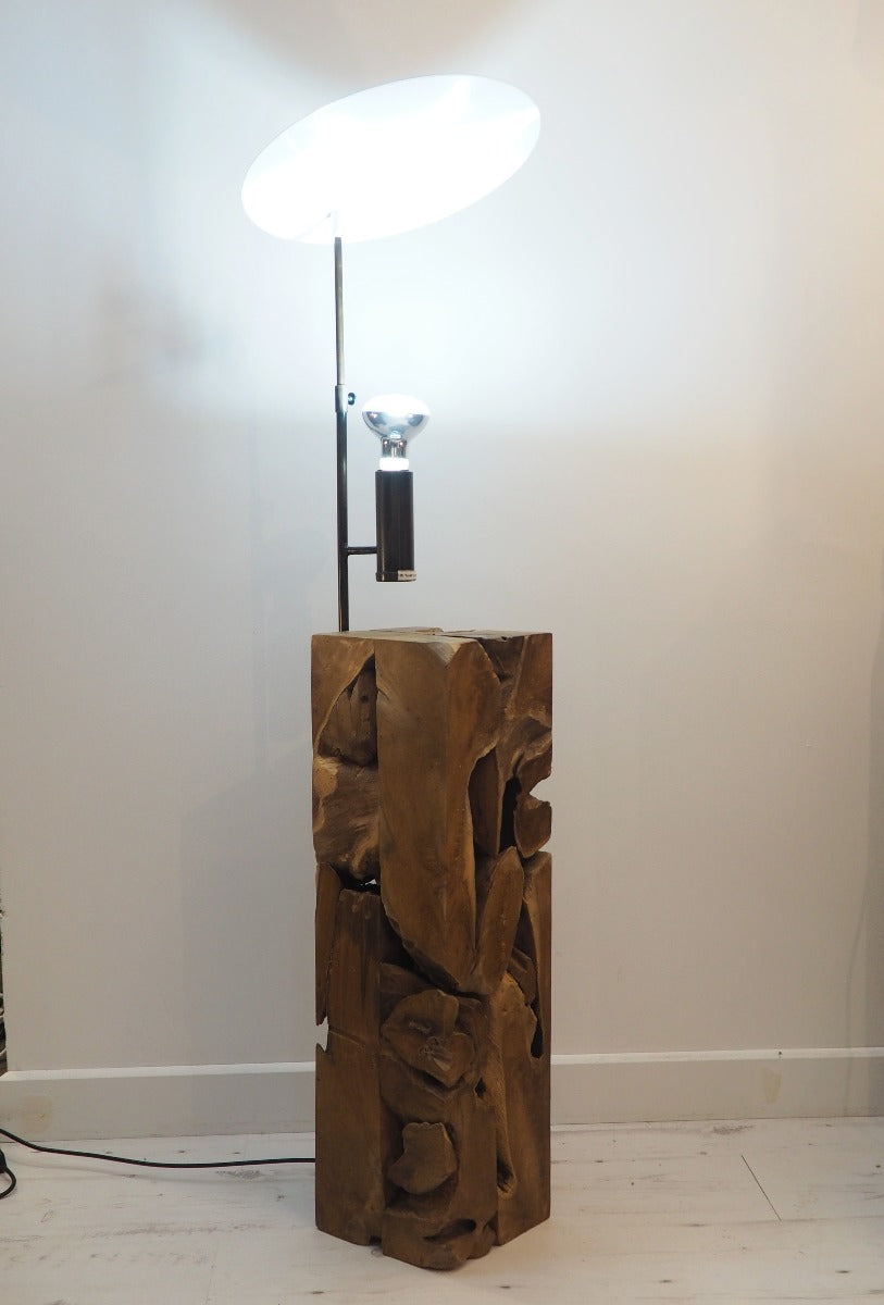 uplighter style floor lamp featuring a chunky wooden base crafted from naturally shaped pieces of teak wood cut as a square column.